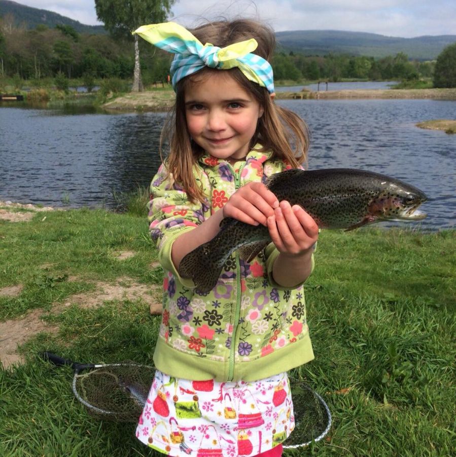 A young girl holding a fish at Rothiemurchus Fishery