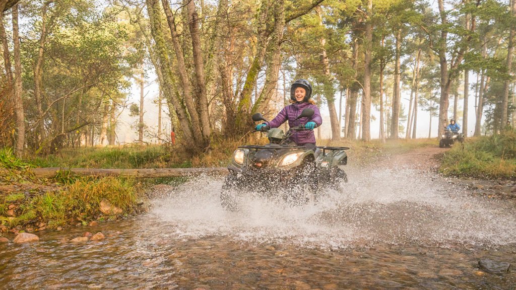 woman on quad bike driving through water