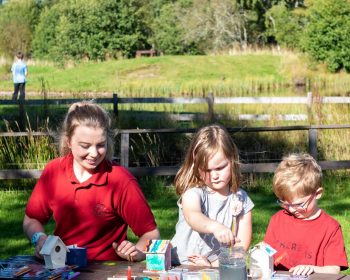 Children and instructor crafting at Rothiemurchus with boy fishing in background