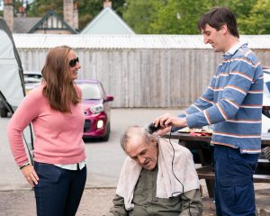 James Grant takes charge of the clippers to shave Neil's hair