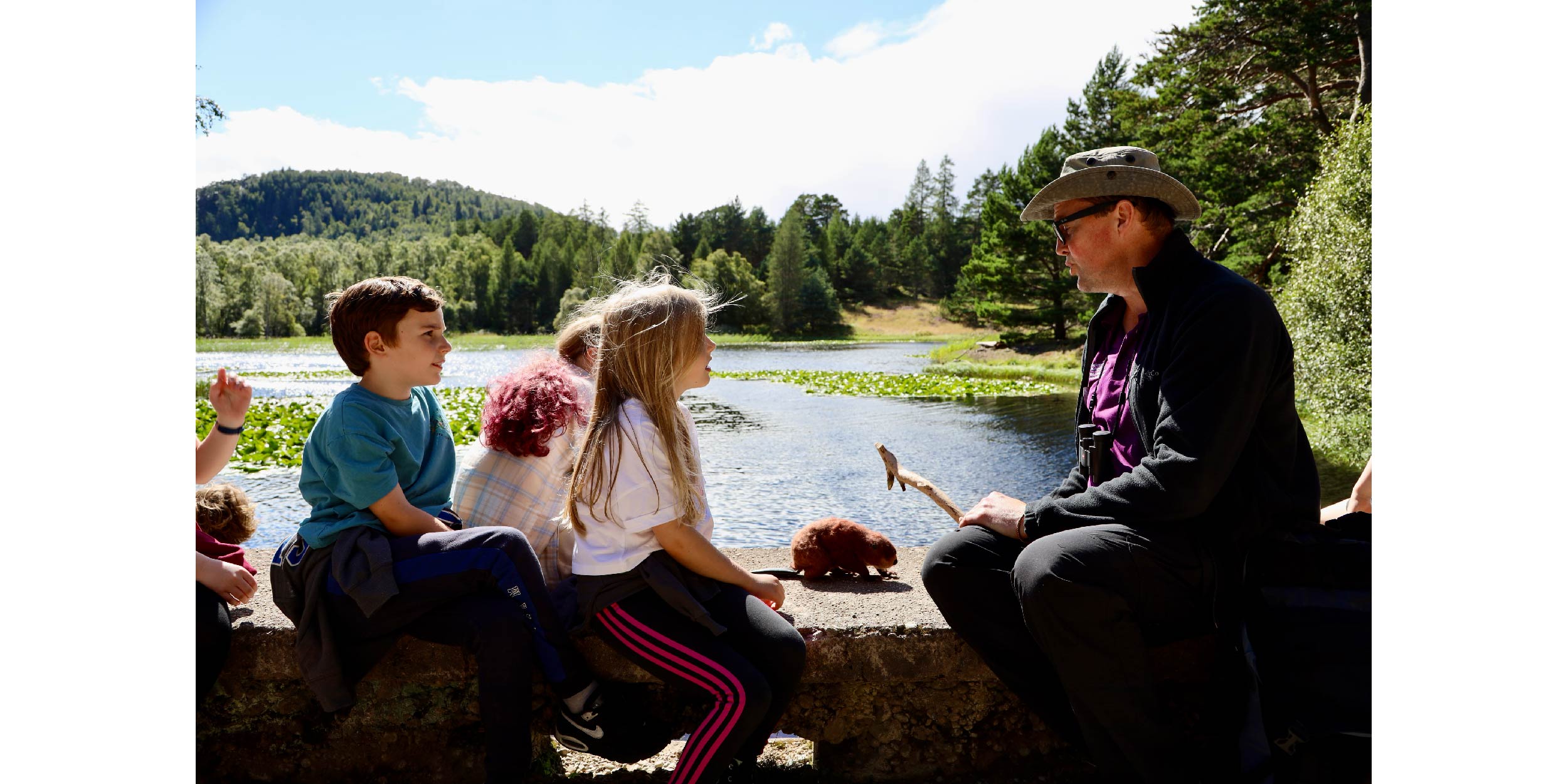 Nature Walk in Beaver habitat. Children sit on a man made dam and listen to Jonathan Willet Beaver Project Manager.